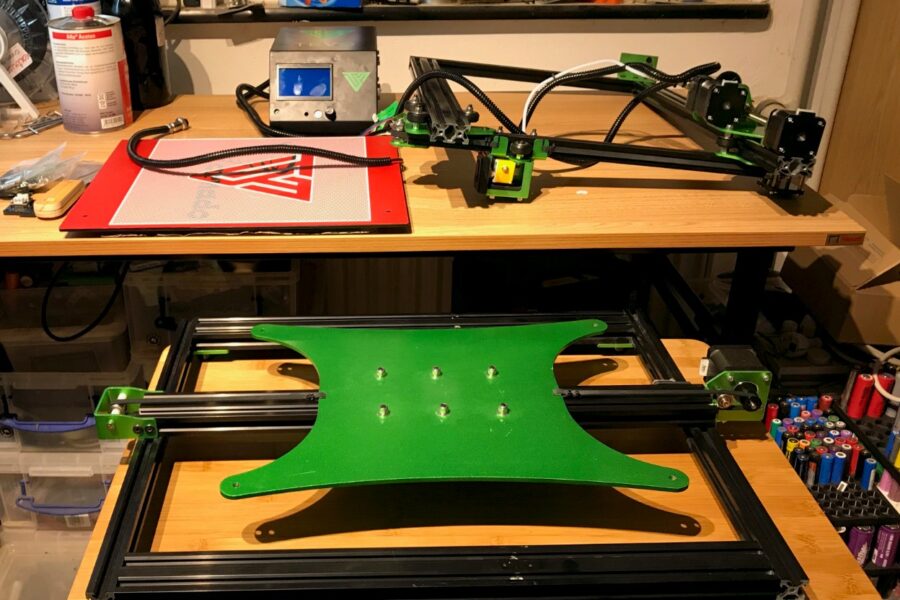 A green and black 3d printer on a table.